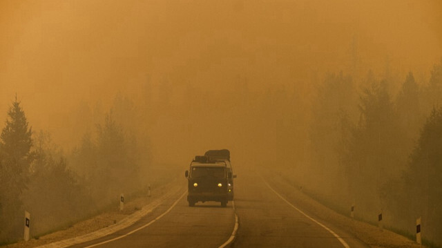Les voitures circulent sur une route enveloppée de fumée provenant des incendies forestiers voisins entre le village de Magaras et la ville de Yakutsk, dans la république de Sakha, en Sibérie, le 27 juillet 2021. Archives. 