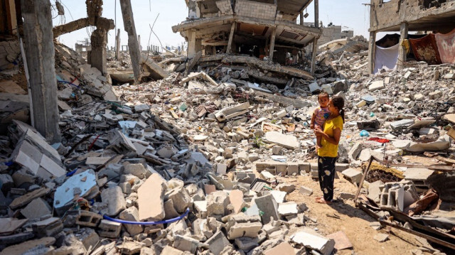 Un enfant tient un bébé dans ses bras, entourée des décombres des bâtiments détruits par les bombardements de l'armée israélienne à Khan Yunis, dans le sud de la bande de Gaza, en Palestine, le 23 juin 2024.