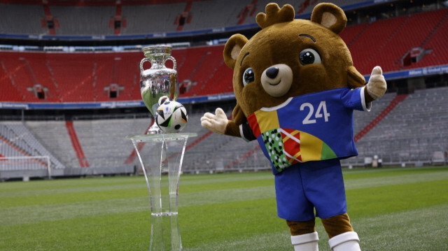 Teddy bear Albaert, mascotte de l'Euro 2024, posant avec le trophée de l'Euro 2024 à l'Allianz Arena de Munich, que tous les favoris se disputeront.