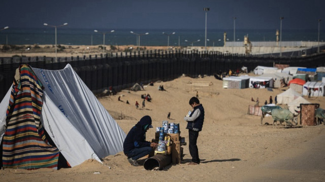 Un Palestinien déplacé présente des marchandises à vendre dans un camp de fortune le long du corridor de Philadelphie ou Salaheddin, une zone tampon étroite le long de la frontière entre la bande de Gaza et l'Égypte, à l'ouest de Rafah, dans le sud de la bande de Gaza, le 14 janvier 2024.