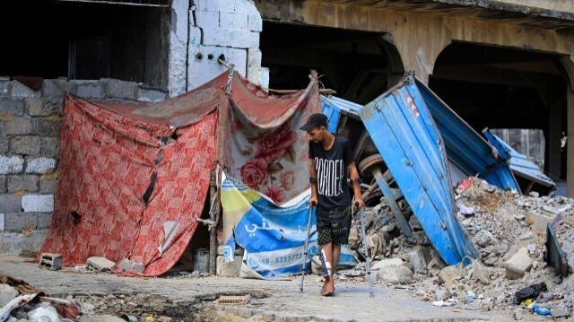 Un Palestinien blessé marche avec des béquilles près d'une tente qui abrite les résidents qui ont perdu leur maison dans le sud de la bande de Gaza, le 30 juin 2024.