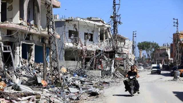 Une moto passant devant des bâtiments détruits par des tirs de l'armée israélienne sur le village libanais d'Aita al-Shaab, près de la frontière avec le nord d'Israël, le 29 juin 2024, dans le cadre des affrontements transfrontaliers entre les troupes israéliennes et les combattants du Hezbollah.