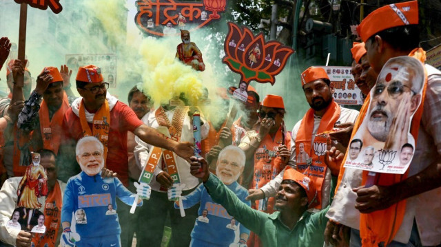 Des partisans de Narendra Modi, Premier ministre indien et chef du Bharatiya Janata Party (BJP), portent ses découpages alors qu'ils célèbrent les résultats du dépouillement des élections générales indiennes à Varanasi, le 4 juin 2024.