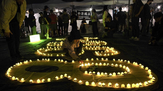 Un garçon place une bougie sur une banderole "8964" lors d'un rassemblement marquant le 35e anniversaire de la répression de la place Tiananmen en 1989, sur la place de la Liberté à Taipei au Taïwan, le 4 juin 2024.