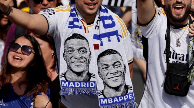 Des supporters du Real Madrid portant des écharpes de football à l'effigie du footballeur français Kylian Mbappé.