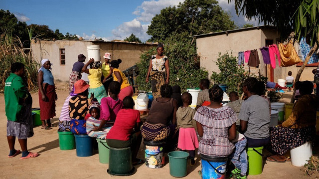 Letwin Mhande (C), trente-six ans, mère de quatre enfants, attend son tour pour charger quatre seaux d'eau par famille et par jour à un puits communautaire à Epworth, un quartier informel à l'est de Harare, la capitale du Zimbabwe, le 23 mai 2024.