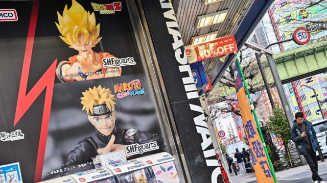 Des piétons passent devant une affiche annonçant la célèbre franchise de mangas " Dragon Ball" dans une rue du quartier d'Akihabara à Tokyo, Au Japon.