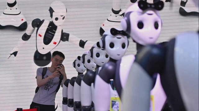 Un homme prend une photo de robots lors de la conférence mondiale sur l'intelligence artificielle (WAIC) à Shanghai, le 7 juillet 2023.