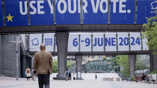 Un piéton passe devant une bannière affichée sur le bâtiment du Parlement européen à Bruxelles, alors que le mouvement Extinction Rebellion prévoit des actes de désobéissance civile pour le climat.