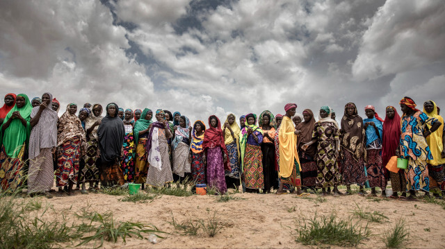 Un groupe de femmes travaillant sur des cultures de sorgho attendent l'arrivée d'un convoi des Nations Unies près du village de Sabon Machi, dans la région de Maradi, au Niger, le 16 août 2018. 