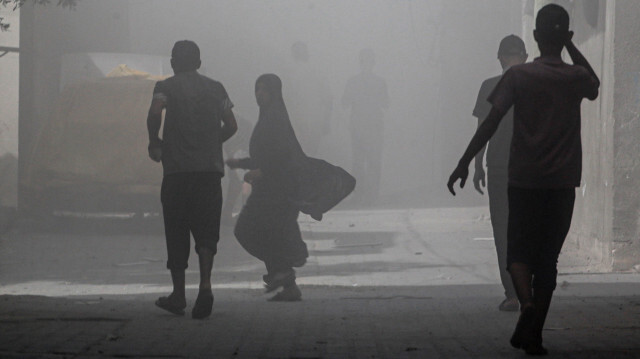 Des Palestiniens marchant dans la fumée et la poussière après une attaque de drones des forces spéciales israéliennes dans le camp de Nuseirat, dans le centre de la bande de Gaza, le 8 juin 2024, dans le cadre du conflit actuel entre Israël et le groupe militant palestinien Hamas.
