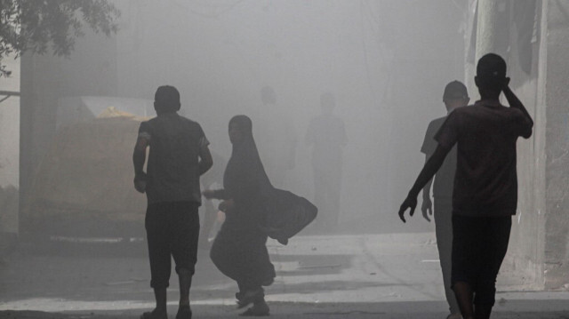 Des Palestiniens marchent dans la fumée et la poussière après une opération des forces spéciales israéliennes dans le camp de Nuseirat, dans le centre de la bande de Gaza, le 8 juin 2024.