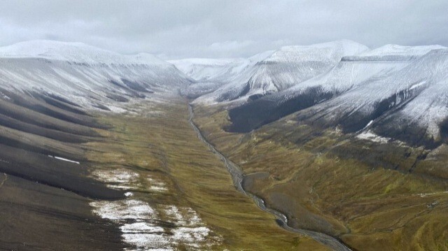 Une vue aérienne capturée depuis un hélicoptère montre des montagnes enneigées et une rivière dans une vallée de l'archipel norvégien arctique du Svalbard, au nord de la Norvège, le 13 septembre 2023.