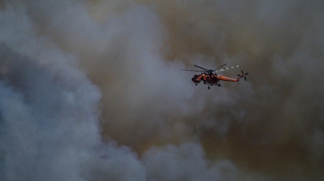 Un hélicoptère vole à travers la fumée au-dessus d'un camp militaire pendant un incendie de forêt à Keratea, près d'Athènes, le 30 juin 2024.