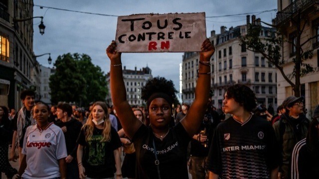 Une manifestante brandit une pancarte "Tous contre le RN" lors d'un rassemblement après l'annonce des résultats du premier tour des élections législatives à Lyon, dans l'est de la France, le 30 juin 2024.