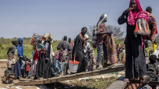 Des réfugiés soudanais et des Sud-Soudanais qui ont fui la guerre au Soudan transportent leurs effets personnels en embarquant sur un bateau sur les rives du Nil blanc dans le port de Renk, le 14 février 2024. 