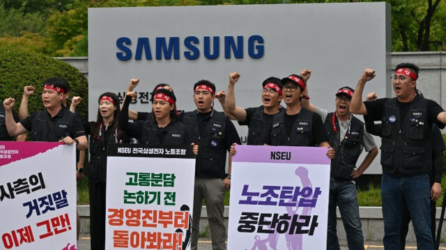 Des membres du syndicat national de Samsung Electronics crient des slogans devant un panneau de Samsung Electronics à l'extérieur du campus Giheung de l'entreprise à Yongin, le 10 juillet 2024.