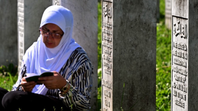 Une survivante musulmane bosniaque du génocide de Srebrenica en 1995, assise entre les pierres tombales alors qu'elle prie à côté des tombes de ses proches, au cimetière commémoratif du village de Potocari, près de la ville de Srebrenica en Bosnie orientale, le 11 juillet 2024, marquant le 29e anniversaire du génocide de Srebrenica.