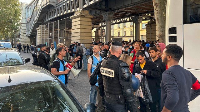 Полиция и сотрудники гуманитарных организаций разговаривают с теми, кто ждет автобуса возле лагеря для бездомных в Париже, Франция.