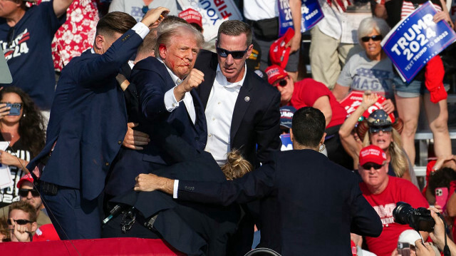 Le candidat républicain Donald Trump est vu avec du sang sur le visage, entouré d'agents des services secrets, alors qu'il est évacué de la scène lors d'un événement de campagne à Butler Farm Show Inc. à Butler, en Pennsylvanie, le 13 juillet 2024. Le candidat républicain Donald Trump a été évacué de la scène lors d'un meeting en Pennsylvanie après que des coups de feu aient été tirés.