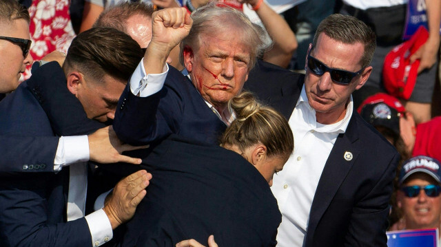 Le candidat républicain Donald Trump est vu avec du sang sur le visage, entouré d'agents des services secrets, alors qu'il est évacué de la scène lors d'un événement de campagne à Butler Farm Show Inc. à Butler, en Pennsylvanie, le 13 juillet 2024. Donald Trump a été touché à l'oreille lors d'une apparente tentative d'assassinat par un homme armé lors d'un rassemblement de campagne samedi, dans un incident chaotique et choquant qui alimentera les craintes d'instabilité à l'approche de l'élection présidentielle américaine de 2024.