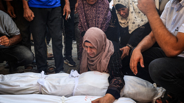 Des femmes palestiniennes pleurant les corps enveloppés de trois enfants tués lors d'un bombardement israélien à Deir el-Balah dans le centre de la bande de Gaza, devant l'hôpital des Martyrs d'al-Aqsa, le 13 juillet 2024. Mohamed Ali al-Rai et ses trois filles, âgées de cinq à neuf ans, ont été tués lors d'un bombardement israélien sur leur maison à Deir el-Balah, a déclaré le Croissant-Rouge palestinien le 13 juillet.