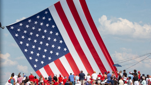 Des partisans de Trump applaudissent alors que le drapeau américain est démêlé lors d'un événement de campagne à Butler Farm Show Inc. à Butler, en Pennsylvanie, le 13 juillet 2024. 