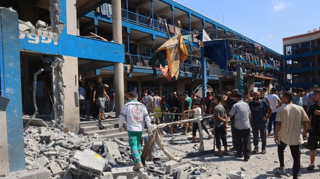 Des Palestiniens constatant les dégâts causés par le bombardement militaire israélien de l'école d'Abu Oreiban, gérée par l'UNRWA (Office de secours et de travaux des Nations Unies pour les réfugiés de Palestine dans le Proche-Orient), transformée en refuge, où vivent des Palestiniens déplacés, dans le camp de réfugiés de Nuseirat, au centre de la bande de Gaza, le 14 juillet 2024, dans le cadre du conflit entre Israël et le groupe militant palestinien Hamas. 