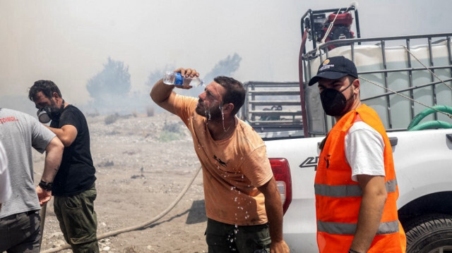 Un homme se rafraîchit le visage avec de l'eau alors que des feux de forêt brûlent près du village de Vati, juste au nord de la ville côtière de Gennadi, dans la partie sud de l'île grecque de Rhodes, le 25 juillet 2023. 