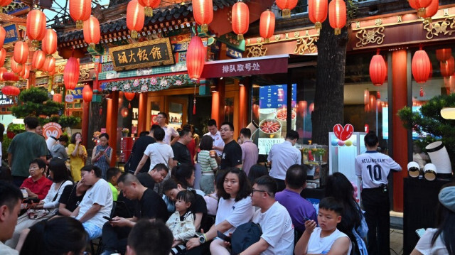 Des personnes attendent leur tour sous des lanternes rouges dans un restaurant de Pékin, le 13 juillet 2024. 