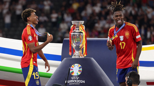 L'attaquant espagnol #19 Lamine Yamal (G) et le milieu de terrain espagnol #17 Nico Williams célèbrant sur le podium après avoir remporté le match de football de la finale de l'UEFA Euro 2024 entre l'Espagne et l'Angleterre à l'Olympiastadion de Berlin, le 14 juillet 2024.