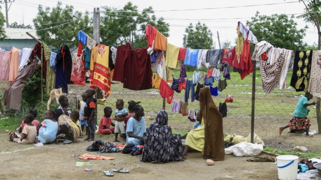 Des familles sont assises sous des cordes à linge alors qu'elles attendent des repas fournis par une initiative caritative dans un camp de déplacés de la ville de Gedaref, dans l'est du Soudan déchiré par la guerre, le 13 juillet 2024.