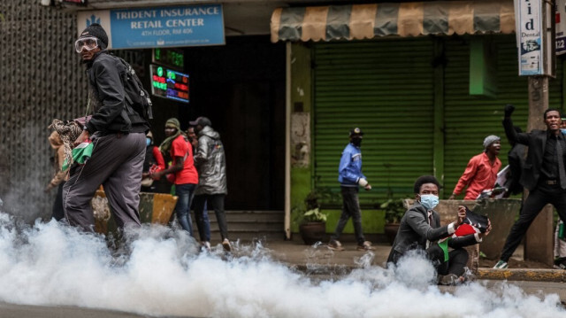 Un manifestant (à droite) brandit un drapeau kenyan alors qu'un nuage de gaz lacrymogène est libéré d'une cartouche lors de nouvelles manifestations à Nairobi, le 16 juillet 2024.