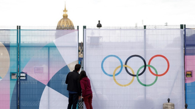 Un couple regarde entre les barrières bordant le site olympique des Invalides à Paris le 16 juillet 2024, avant les Jeux Olympiques et Paralympiques de Paris 2024.