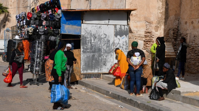 Des migrants d'Afrique subsaharienne sont assis avec leurs affaires à l'extérieur d'un marché dans la ville portuaire tunisienne de Sfax, le 23 avril 2024. 