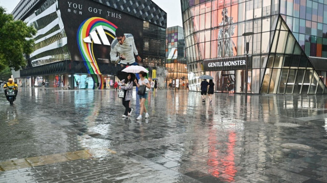 Des personnes utilisent des parapluies pour s'abriter des fortes pluies à Pékin, le 12 juillet 2024.