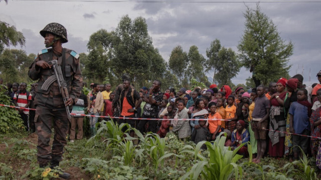 Un soldat monte la garde alors que des spectateurs assistent à une cérémonie d'enterrement des victimes d'un attentat à la bombe dans un camp de personnes déplacées près de Goma, à Kibati, en République démocratique du Congo, le 15 mai 2024. 