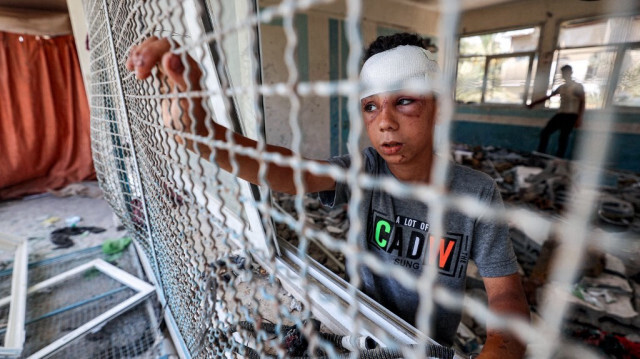 Un enfant palestinien gravement blessé près d'un treillis de fenêtre d'une salle de classe d'une école gérée par l'Office de secours et de travaux des Nations Unies pour les réfugiés de Palestine (UNRWA) détruite par les bombardements israéliens, dans le camp de Nuseirat dans le centre de la bande de Gaza, en Palestine, le 7 juin 2024. 