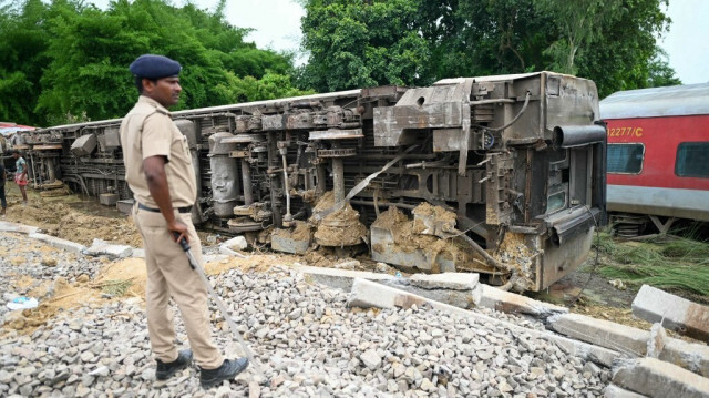 Un policier se tient près du train qui a déraillé dans le district de Gonda, dans l'État indien de l'Uttar Pradesh, le 19 juillet 2024.