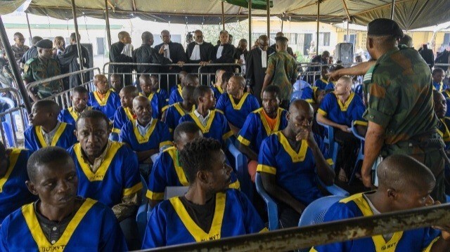 Un officier (R) fait un geste alors que les conseillers et les accusés d'une tentative de coup d'état manquée sont assis lors de la première audience du procès à la prison de Ndolo à Kinshasa le 7 juin 2024. 