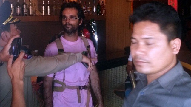 Un policier cambodgien (G) parle à l'activiste environnemental espagnol Alejandro Gonzalez-Davidson (C) qui a été arrêté dans un restaurant à Phnom Penh le 23 février 2015. 