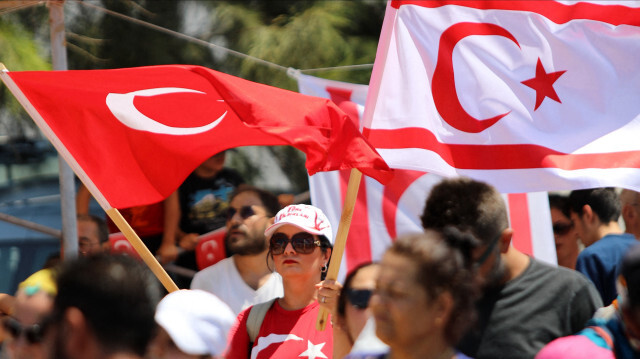 Des personnes agitant un drapeau turc (à gauche) et un drapeau de la République turque de Chypre du Nord (RTCN) lors d'une parade militaire, le 20 juillet 2024.