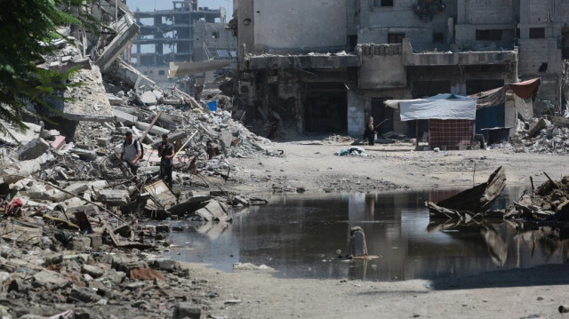 Une mare d'eau stagnante remplit un creux dans la route entre les bâtiments détruits par les bombardements israéliens précédents, à Khan Yunis dans le sud de la bande de Gaza, le 19 juillet 2024.