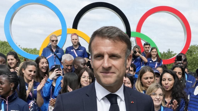 Le président de la République française, Emmanuel Macron après avoir posé avec des athlètes français lors d'une visite au village olympique, avant la cérémonie d'ouverture des Jeux olympiques et paralympiques de Paris 202, à Saint-Denis, dans le nord de Paris, le 22 juillet 2024.