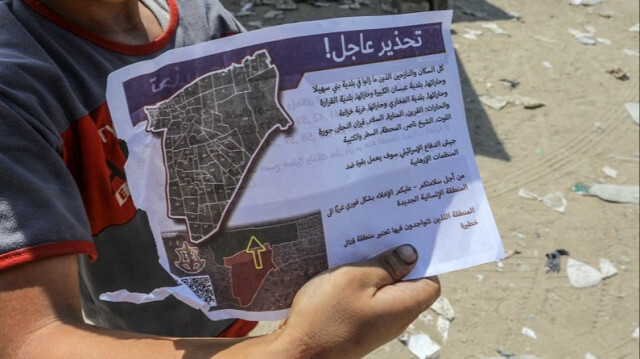 Un enfant palestinien montre un tract largué par les forces israéliennes à l'est de la ville de Khan Younès, exhortant les résidents à se déplacer vers l'ouest de la ville à Gaza, le 22 juillet 2024.