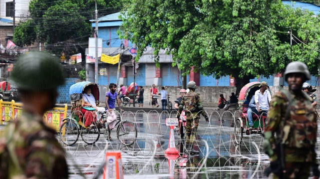 Des membres de l'armée bangladaise montent la garde près de barricades en fil de fer barbelé, dans le cadre d'un couvre-feu instauré à la suite d'affrontements entre la police et des manifestants, à Dhaka, le 22 juillet 2024.