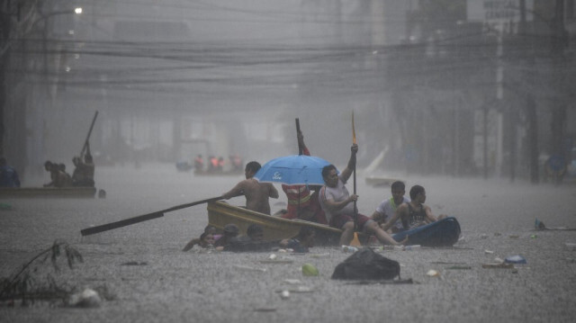 Des sauveteurs pagaient sur leurs bateaux le long d'une rue inondée à Manille le 24 juillet 2024, suite aux fortes pluies provoquées par le typhon Gaemi.