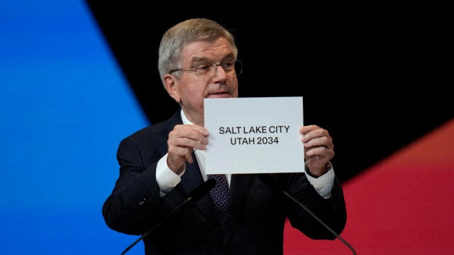 Le président du Comité international olympique (CIO), Thomas Bach, montre une pancarte indiquant que Salt Lake City a été choisie pour être la ville hôte des Jeux d'hiver de 2034, à Paris le 24 juillet 2024.