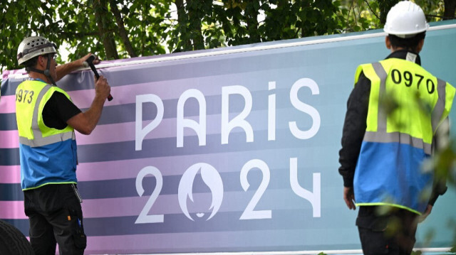 Des ouvriers accrochent une banderole des JO 2024 à une clôture de la South Paris Arena à Paris le 24 juillet 2024.
