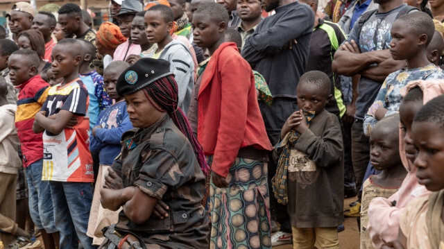 Une soldate est assise et regarde, avec des membres du public, des soldats de l'armée de la République démocratique du Congo assister à leur procès à Lubero, le 6 juillet 2024.